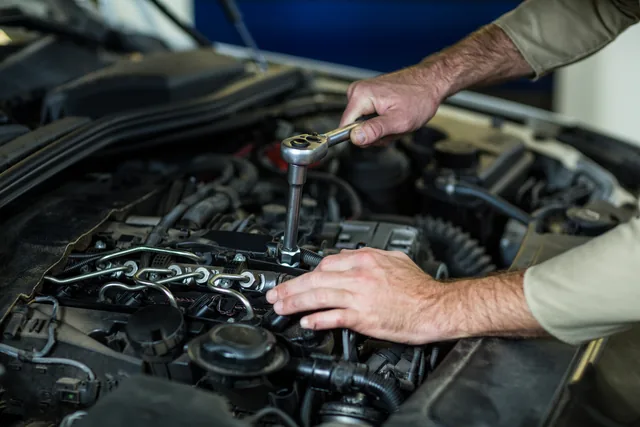 Mechanic using a ratchet to service a car engine