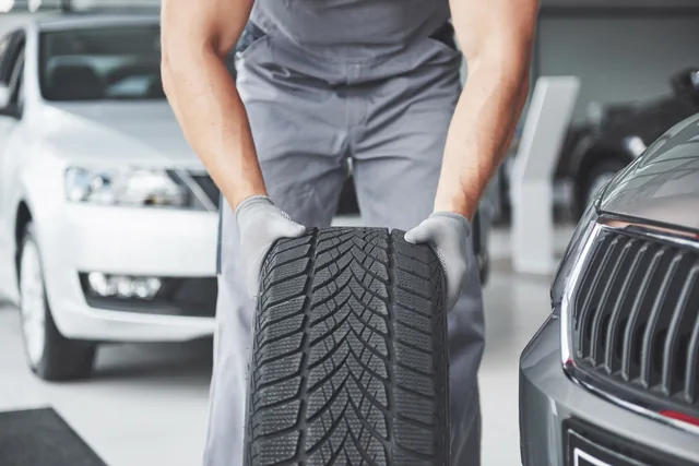 Mechanic holding a new car tyre in a workshop