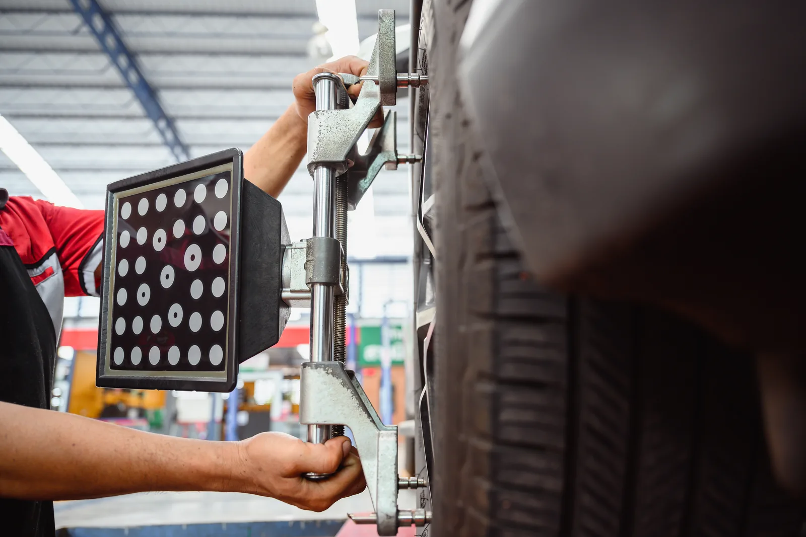 Mechanic fitting a wheel alignment sensor to a vehicle wheel